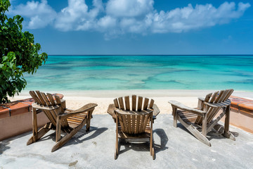 Wooden beach chairs facing the clear tropical ocean