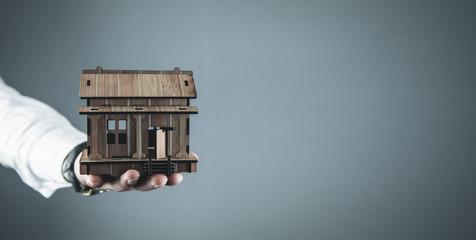 Real estate agent holding wooden house. Real estate concept