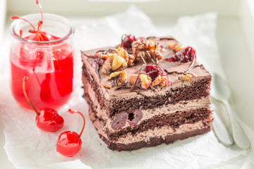 Closeup of sweet chocolate cake with walnuts and cherries