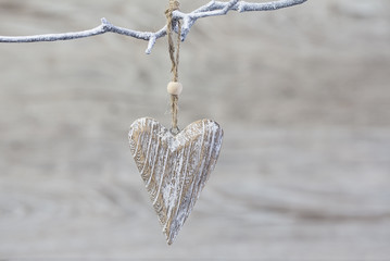 White wooden heart hanging from a branch on a cold winter day