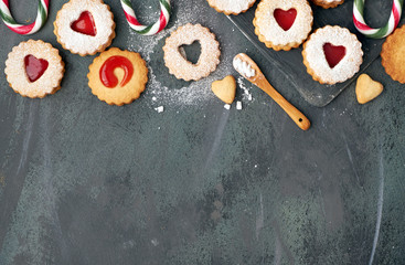 Top view of traditional Christmas Linzer cookies with strawberry jam in wooden tray on dark, copy-space