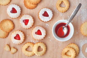 Top view of traditional Christmas Linzer cookies filled with strawberry jam on wooden board