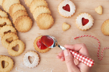 Top view of traditional Christmas Linzer cookies filled with strawberry jam on wooden board.