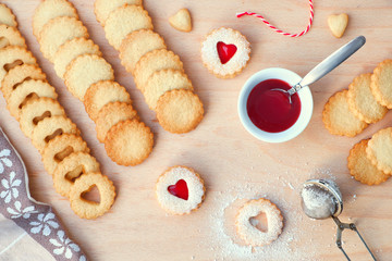 Top view of traditional Christmas Linzer cookies filled with strawberry jam on wooden board