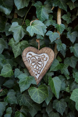 decorative wooden heart hanging on a ivy covered wall