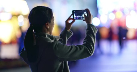 Woman use of cellphone to take photo in the carnival party at night