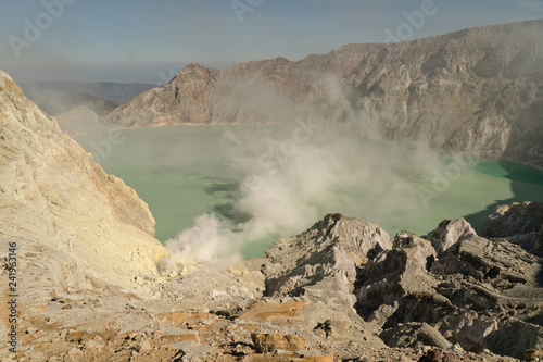 Plakat Krater z kwaśnym jeziorem krateru, Kawah Ijen słynną atrakcją turystyczną, w której wydobywa się siarkę. Ekstrakcja siarki w kraterze wulkanu. Gaz siarkowy, dym.
