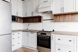 Luxury modern kitchen furniture in grey color and steel oven,fridge, sink, wooden tabletop. Gray cabinets in scandinavian style. Home renovation. Stylish kitchen interior design.