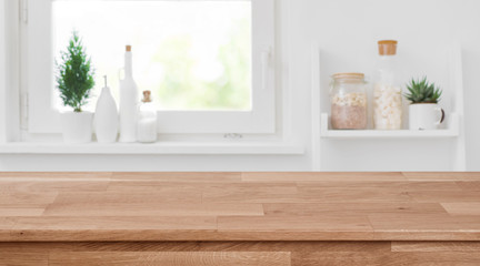 Wooden tabletop in front of blurred kitchen window, shelves background