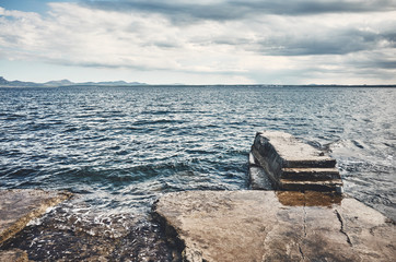 Seascape with a concrete pier, color toned picture.