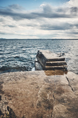 Seascape with a concrete pier, color toned picture.
