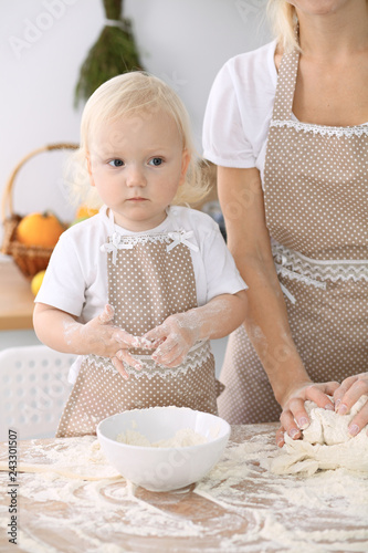 Plakat Mała dziewczynka i jej blondynki mama w beżowych fartuchach bawić się i śmia się podczas gdy ugniatający ciasto w kuchni. Domowe ciasta na chleb, pizzę lub upiecz ciasteczka. Rodzinna zabawa i gotowanie koncepcji