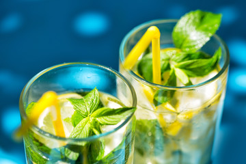 Fragment of glasses of lemonade on blue background