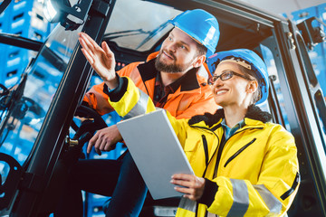 Workers in logistics warehouse checking the inventory with data being supplied by an erp system