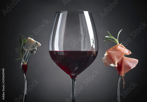 Plakat Kieliszek czerwonego wina z serem pleśniowym, rozmarynem i prosciutto.