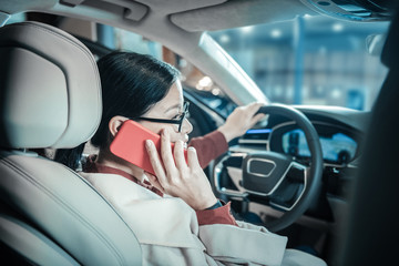 Dark-haired woman calling her children while driving home