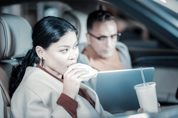 Husband and wife eating junk food sitting in their car