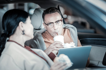 Husband drinking coke and listening to his stylish wife