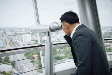 Businessman with binoculars on the top of building searching for golden opportunity concept