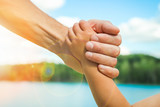 hands of a parent and child in nature in a park by the sea