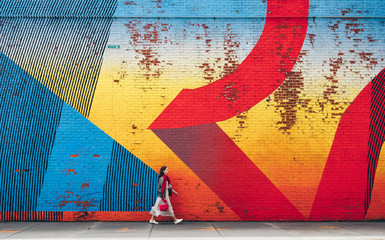 Young girl walking by the wall with graffiti