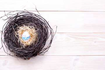 Egg in a nest on a light wooden background.