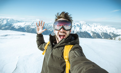 Portrait of an andsome man is taking a selfie in the snow on a mountain at winter