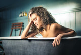 Melancholic girl sitting in a bathtub