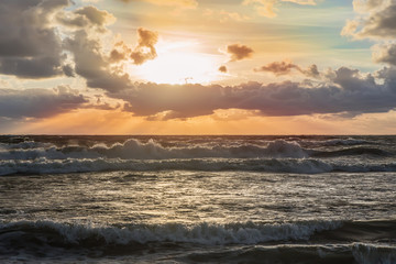 sunset in the cloudy sky over the stormy sea