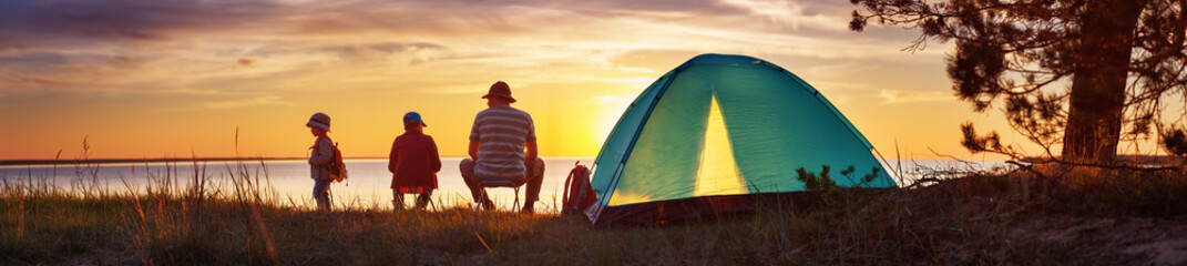 Family resting with tent in nature at sunset