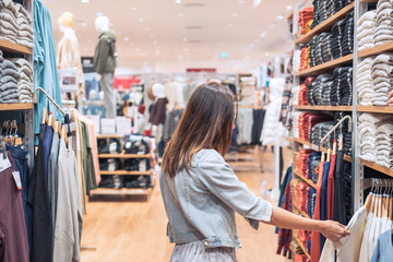 Young asian woman choosing clothes in clothing store at the mall, woman shopping lifestyle concept