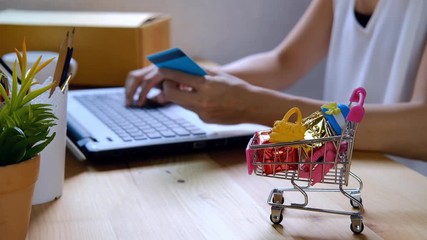 Young woman holding credit card and entering security code for payment online shopping at home