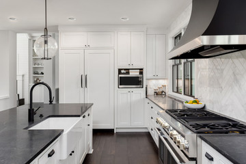 Beautiful Kitchen With Farmhouse Sink, Dark Soapstone Counters, Kitchen Island, and Refrigerator