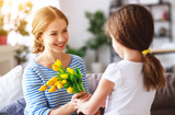 happy mother's day! child daughter gives mother a bouquet of flowers to tulip and gift