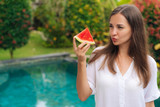 Portrait thoughtful girl with long hair holding slice of watermelon in her hand