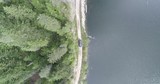 AERIAL: Birdseye view of a truck driving down dirt road beside a lake.