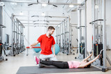 Young girl exercising on the decompression simulators with trainer during the spine treatment at the rehabilitation gym