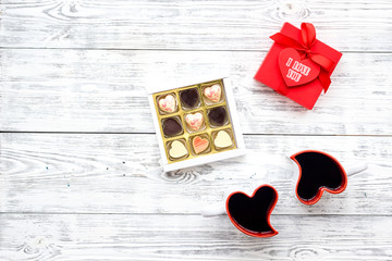 Valentine's day concept. Sweets, red gift box, heart-shaped mugs on white wooden background top view space for text