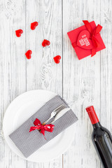 Valentine's day dinner concept. Decorated dishes, tableware, wine, gift box on white wooden background top view