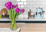 Purple tulips in a glass jar standing on the modern kitchen