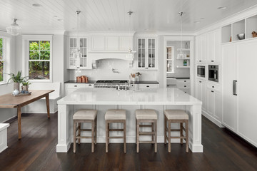Beautiful White Kitchen in New Luxury Home. Features Large Island, Pendant Lights, Hardwood Floors, and High End Appliances.