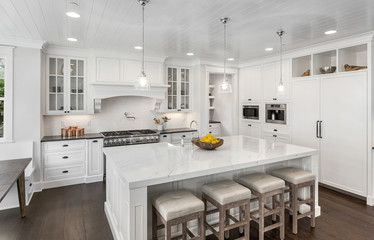 Beautiful White Kitchen in New Luxury Home. Features Large Island, Pendant Lights, Hardwood Floors, and High End Appliances.