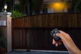 Woman hand using remote control to open the automatic gate in the evening. The auto gate and security system.