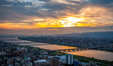 Panoramic, scenic view of Japan's Osaka city from the observatory deck of Umeda Sky Building during sunset with dramatic clouds in the blue and orange sky.
