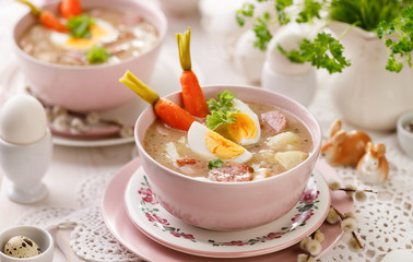 Bowl of sour soup (Żurek), polish Easter soup with the addition of sausage, hard boiled egg and vegetables in a ceramic bowl. Traditional Easter dish in Poland