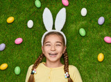 Laughing girl in bunny ears lying on grass