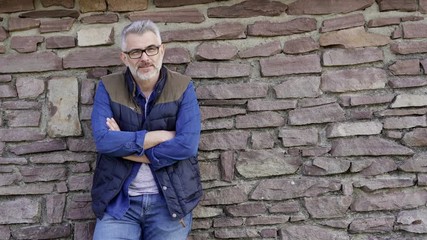 Man standing and leaning on stone wall