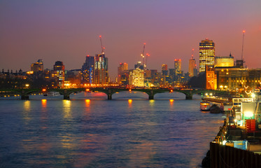 Westminster bridge illuminated in evening lights and the city of London in England, UK