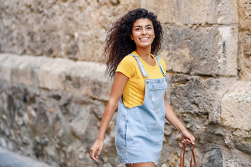 Young black tourist woman with curly hairstyle outdoors