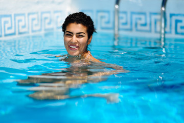 Happy young woman relaxing in swimming pool.